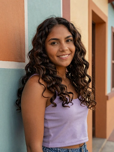 Cindy, 23, Honduran single from Choloma in lavender top against colorful wall - verified dating profile
